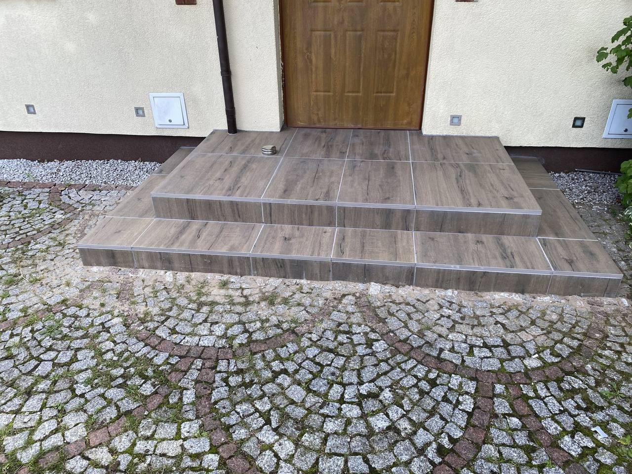 Wykończony taras i schody wejściowe z płytek imitujących drewno